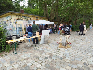 Bautag im Parkcafé Rehberge, in der Mitte Kuchen- und Waffelverkauf vom Parkcafé Das Foto zeigt eine gepflasterte Freifläche im Parkcafé Rehberge. Hier stehen verschiedene Stände, an denen Studierenden Kuchen und Waffeln verkaufen. Die Studierenden stehen vor einer