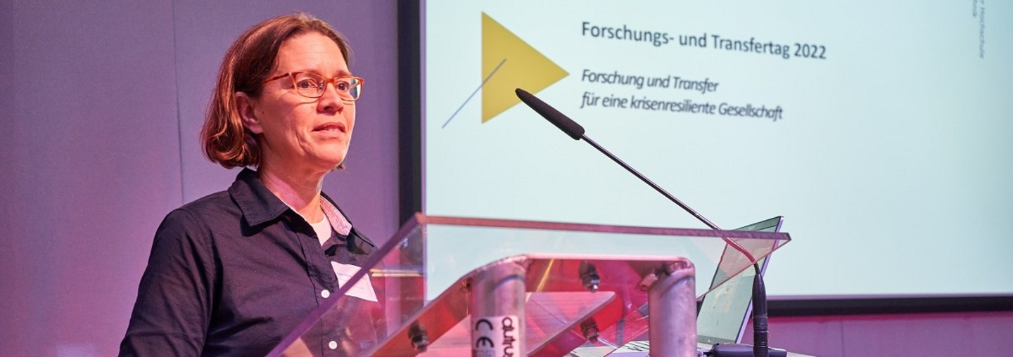 Prof. Dr.-Ing. Silke Köhler, Vizepräsidentin für Forschung, steht auf der Bühne. An der Wand hinter ihr ist zu lesen: „Forschungs- und Transfertag 2022. Forschung und Transfer für eine krisenresiliente Gesellschaft“
