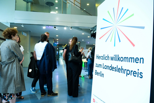 Banner "Landeslehrpreis Berlin 2026", daneben stehen Menschen