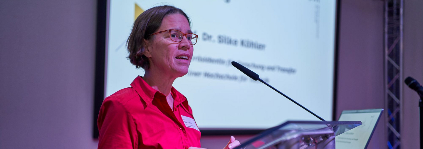Prof. Dr.-Ing. Silke Köhler steht an einem Pult und spricht in ein Mikrofon. Hinter ihr ist „Eröffnung“ zu lesen.