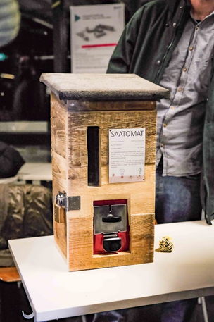 Der Saatgutautomat für das Himmelbeet. Oben kann eine 20 Cent Münze eingeworfen werden, dann dreht man den Hebel und eine Saatgutbombe fällt heraus. Der Automat ist mit Holz verkleidet.