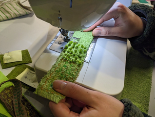 die Studierenden haben an der Nähmaschine eine spezielle Technik entdeckt, um Pflanzen auch haptisch erfahrbar zu machen - es entstehen Fädenbüschel auf dem Stoffrest