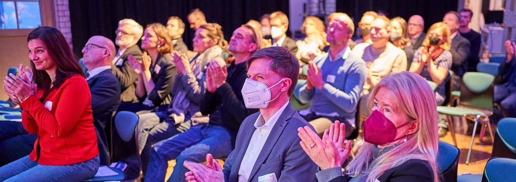 Das Publikum, viele klatschen. Manche tragen eine FFP2-Maske.